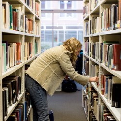 Person choosing book from shelf in library