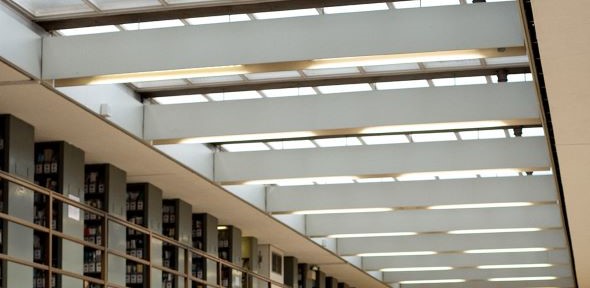 A row of roof girders crosses the image horizontally. To the left of the image is a row of shelves containing pigeonholes. 