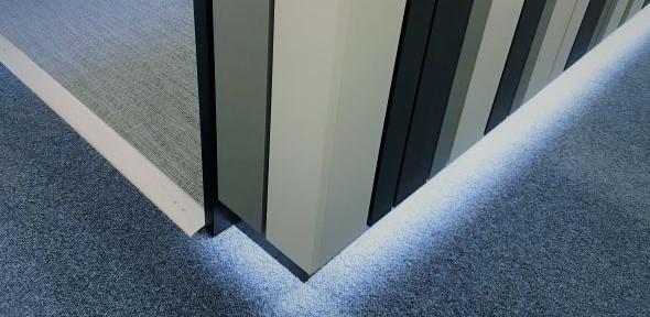 Picture shows the corner of the Safepod which is made of strips of different-coloured metal, and is lit from underneath creating a glow on the carpet