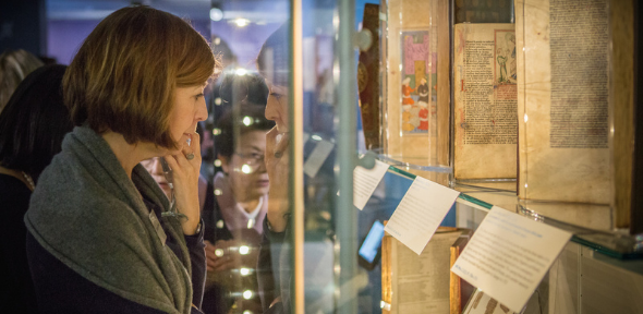 Image of a Friend looking at manuscripts in an exhibition case.